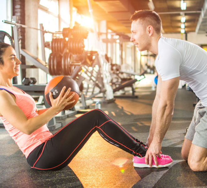 Personal trainer working with his client at a gym.